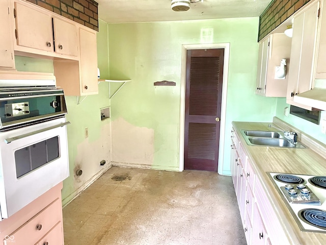 kitchen with a sink, white appliances, and light countertops