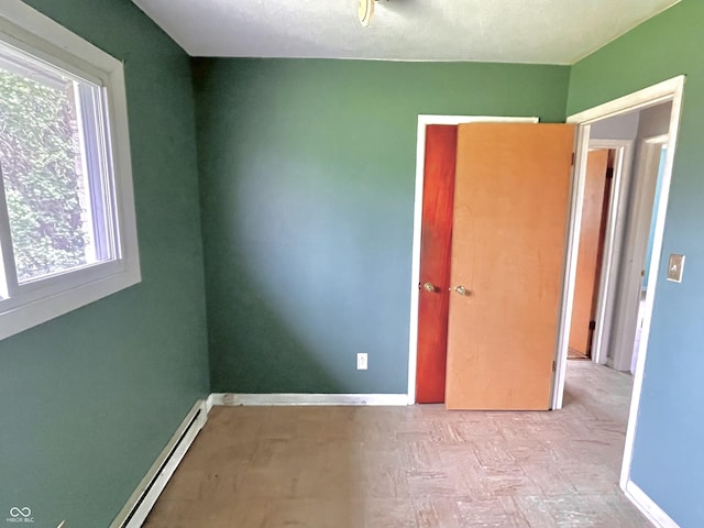 unfurnished bedroom featuring a baseboard heating unit and baseboards
