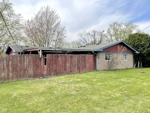 view of side of home featuring a yard, stone siding, and fence