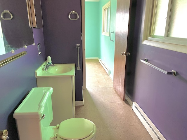 half bath featuring toilet, vanity, a baseboard heating unit, baseboards, and baseboard heating