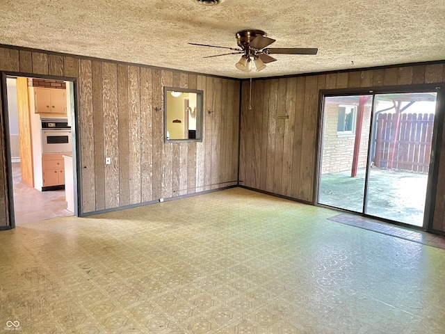spare room featuring a ceiling fan, tile patterned floors, and wooden walls