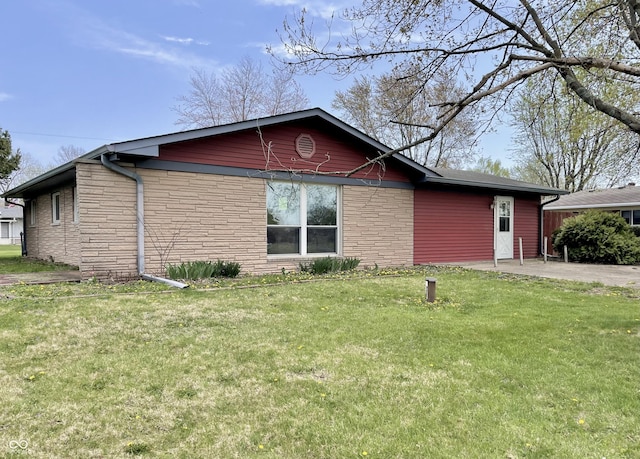 view of side of property with stone siding and a lawn