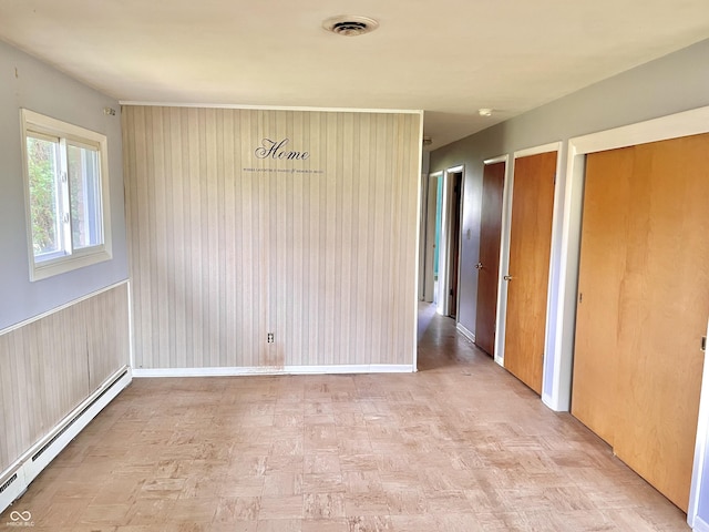 empty room with a baseboard heating unit and visible vents