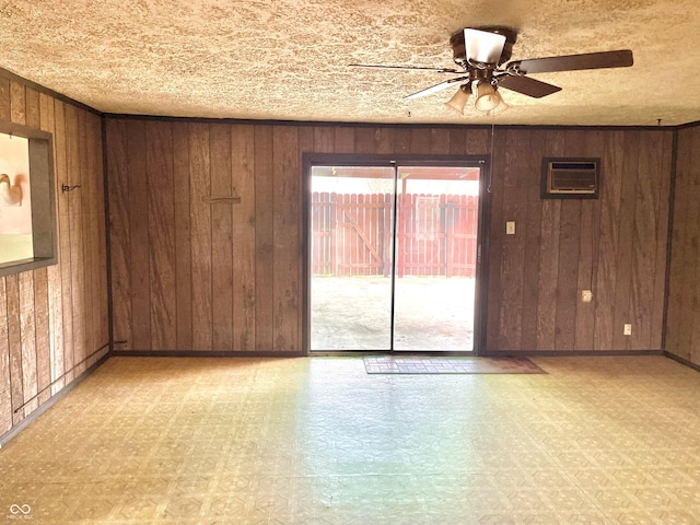 spare room with a wall unit AC, baseboards, ceiling fan, light floors, and wooden walls