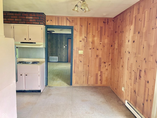 unfurnished room featuring visible vents, wood walls, baseboard heating, and an inviting chandelier