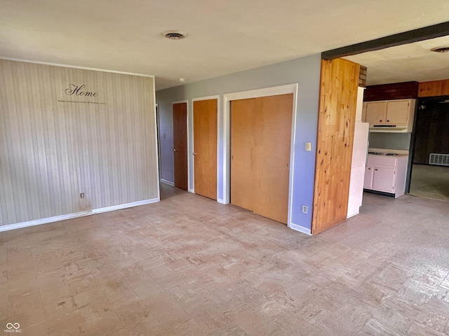 unfurnished bedroom featuring light floors, baseboards, and two closets