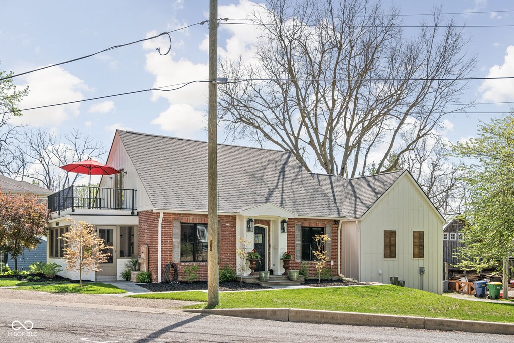 775 W Hawthorne St, Zionsville, IN 46077 - tudor house featuring brick siding, a balcony, roof with shingles, and a front lawn