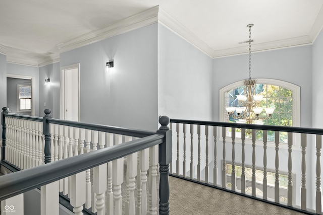 corridor featuring an upstairs landing, carpet floors, a notable chandelier, and ornamental molding