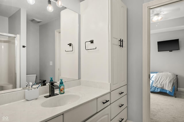 bathroom with a shower with shower door, visible vents, toilet, vanity, and baseboards