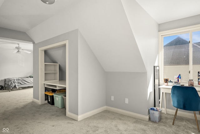 carpeted office space with vaulted ceiling, a ceiling fan, and baseboards
