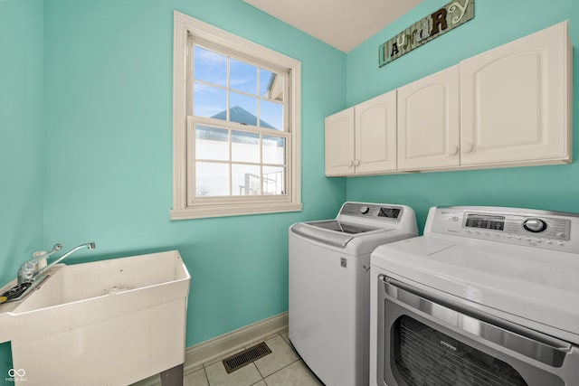 washroom with washing machine and clothes dryer, a sink, cabinet space, baseboards, and visible vents