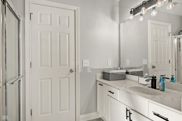 bathroom with baseboards, vanity, and a shower with door