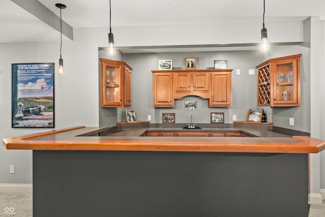 kitchen featuring a peninsula, baseboards, dark countertops, and a sink