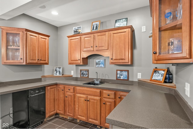 kitchen featuring brown cabinets, dark tile patterned floors, a sink, and glass insert cabinets