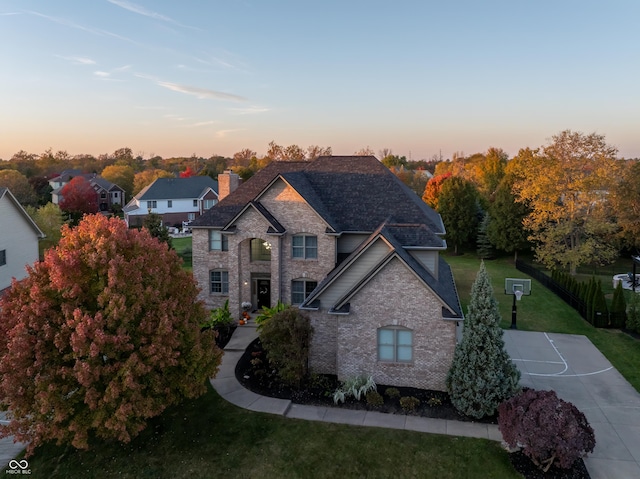 view of front of house with a chimney, a front lawn, brick siding, and a shingled roof