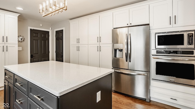 654 E 79th St, Indianapolis, IN 46240 - kitchen with appliances with stainless steel finishes, white cabinetry, wood finished floors, a center island, and recessed lighting