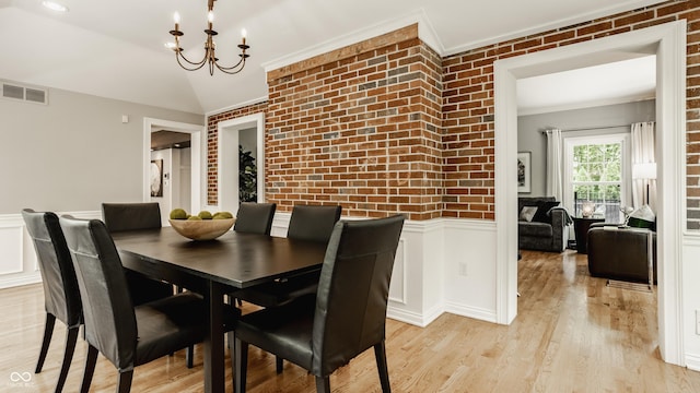 654 E 79th St, Indianapolis, IN 46240 - dining area with brick wall, a chandelier, wainscoting, crown molding, and light wood finished floors