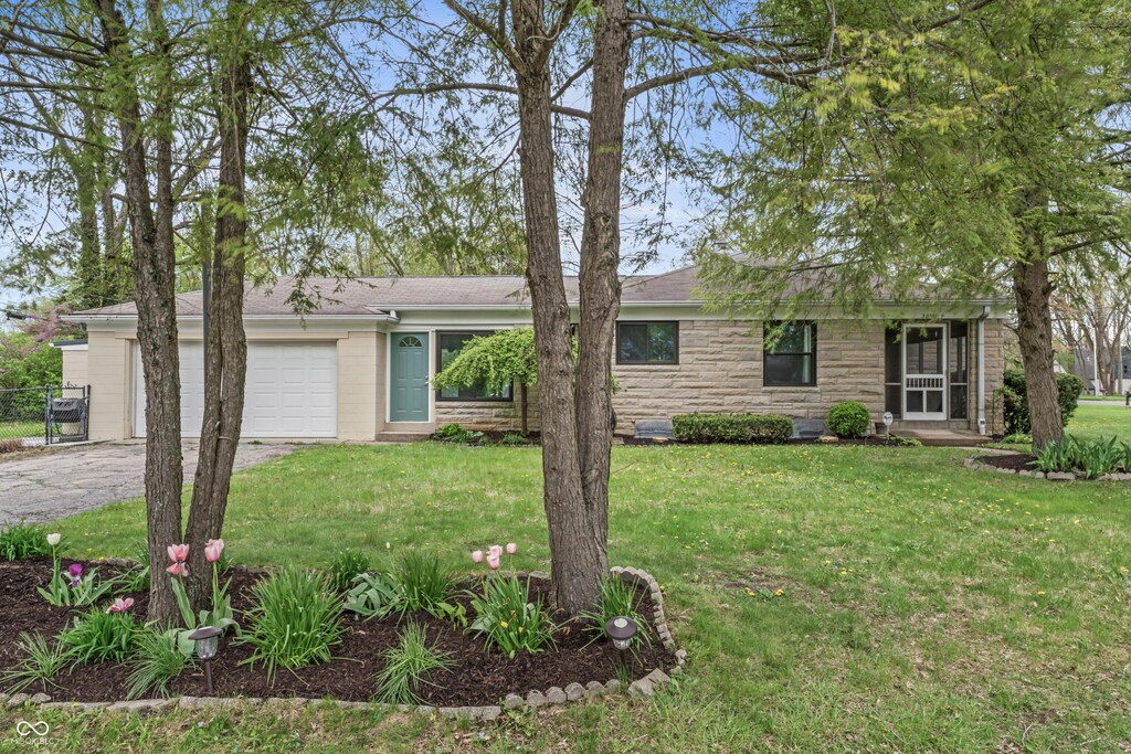 single story home featuring an attached garage, driveway, stone siding, and a front lawn