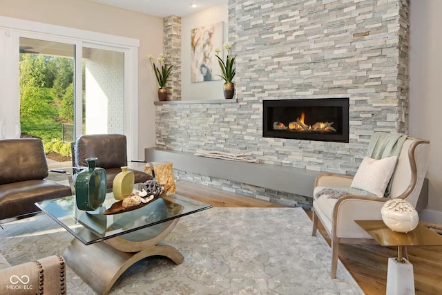 living area with wood finished floors and a stone fireplace