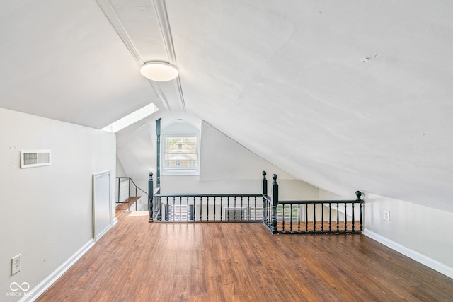 bonus room featuring lofted ceiling, visible vents, wood finished floors, and baseboards
