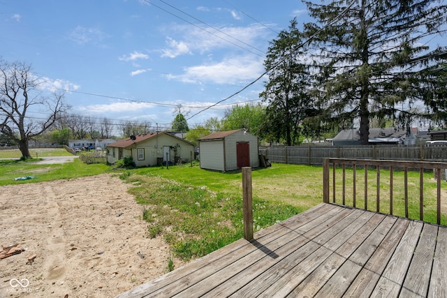 wooden terrace featuring a yard, an outbuilding, a shed, and a fenced backyard