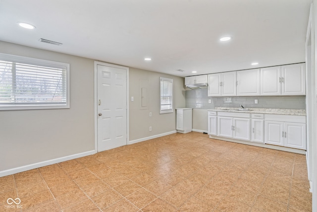 kitchen featuring a sink, baseboards, white cabinetry, and visible vents