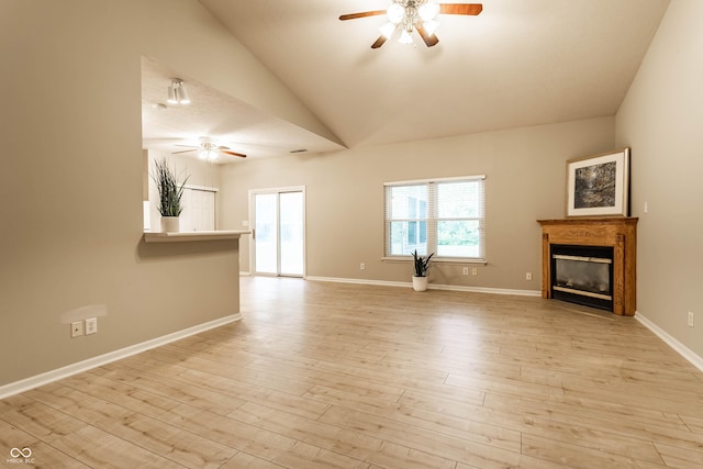 unfurnished living room with ceiling fan, a glass covered fireplace, wood finished floors, lofted ceiling, and baseboards