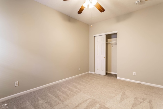 unfurnished bedroom with carpet flooring, baseboards, a closet, and a ceiling fan