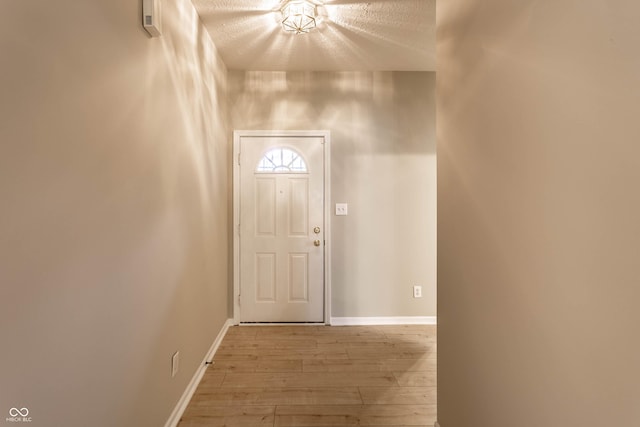 doorway with wood-type flooring, baseboards, and a textured ceiling