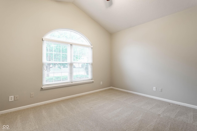 empty room featuring plenty of natural light, light carpet, vaulted ceiling, and baseboards