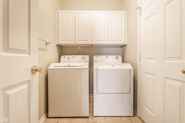 clothes washing area with cabinet space, separate washer and dryer, and light wood-style flooring