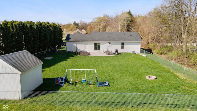 back of house featuring a lawn, a fenced backyard, a patio, and a playground