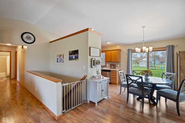 dining space with hardwood / wood-style flooring, vaulted ceiling, and a notable chandelier