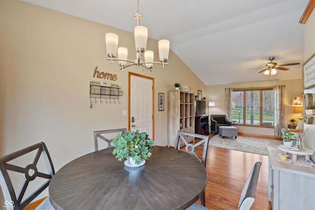 dining space featuring baseboards, vaulted ceiling, wood finished floors, and ceiling fan with notable chandelier