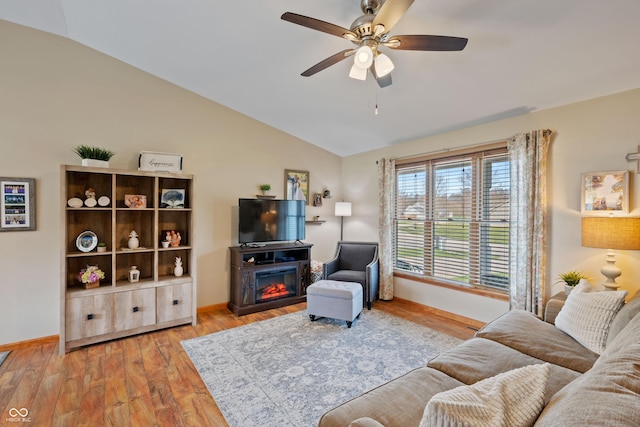 living area with light wood-style floors, lofted ceiling, baseboards, and ceiling fan