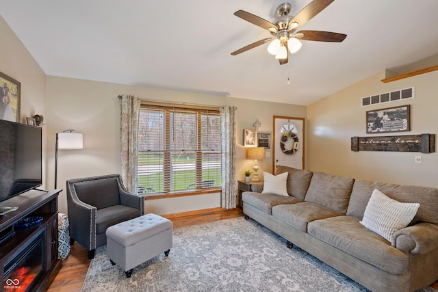living area featuring vaulted ceiling, wood finished floors, visible vents, and ceiling fan