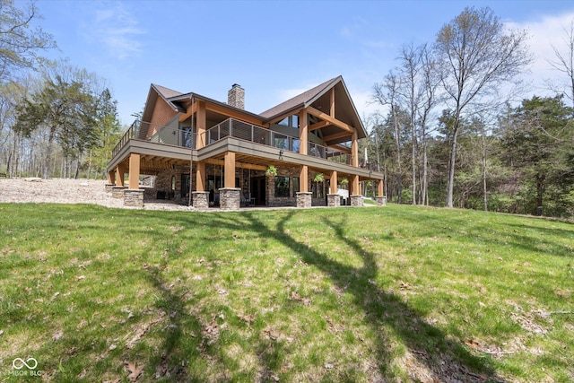 back of property featuring stone siding, a chimney, a yard, and a deck