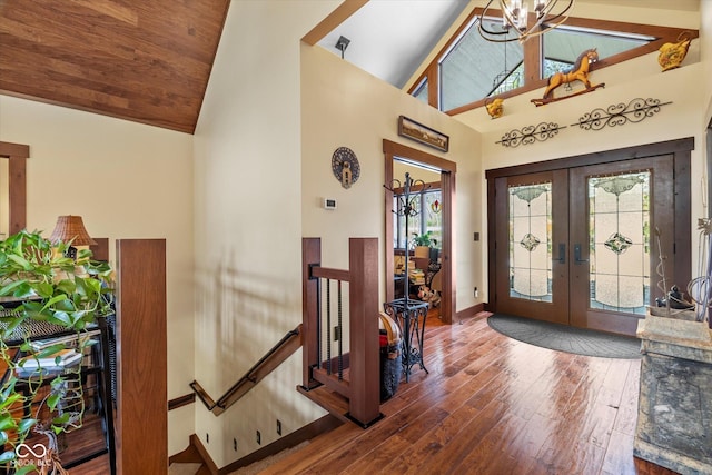 foyer entrance featuring french doors, hardwood / wood-style floors, high vaulted ceiling, baseboards, and a chandelier