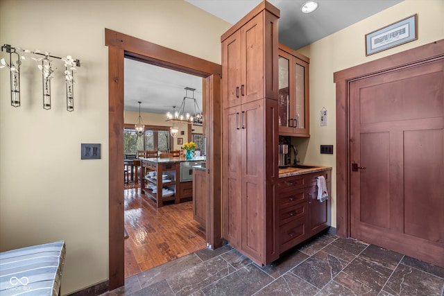 hall with a chandelier and dark stone finish floors