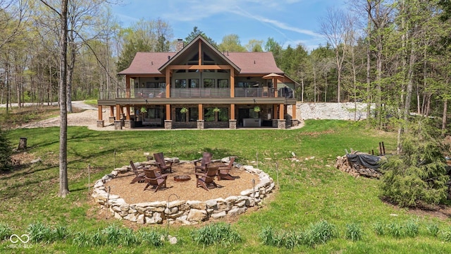 rear view of house featuring an outdoor fire pit, a yard, a chimney, and a patio area