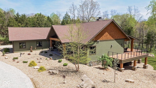 rear view of property with a wooden deck, roof with shingles, and a chimney