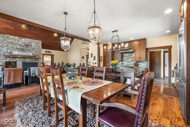 dining room featuring dark wood-style floors, a fireplace, recessed lighting, and a chandelier