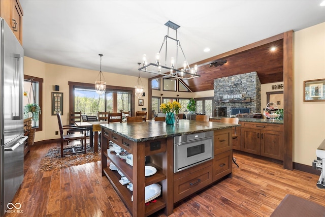 kitchen with stainless steel refrigerator, dark countertops, a chandelier, open shelves, and dark wood-type flooring