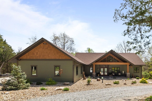 back of house with french doors and roof with shingles