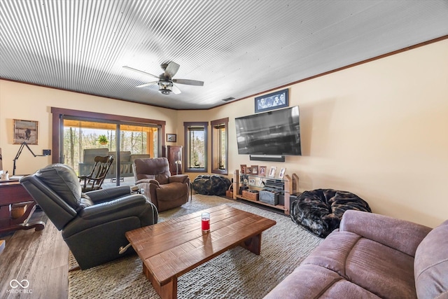 living area with ceiling fan, wood finished floors, and ornamental molding