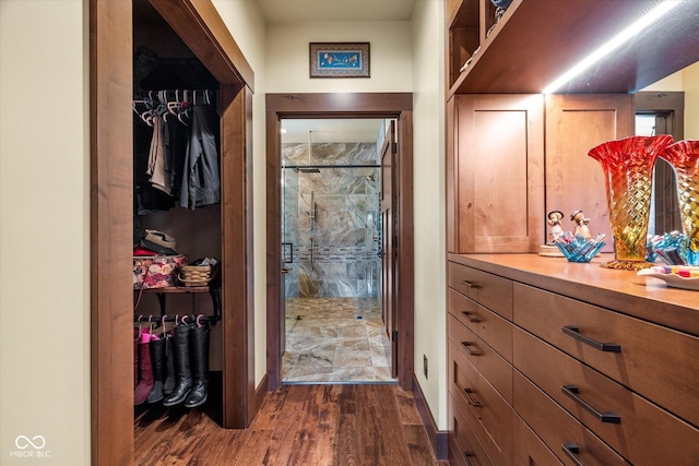 walk in closet with dark wood-style floors