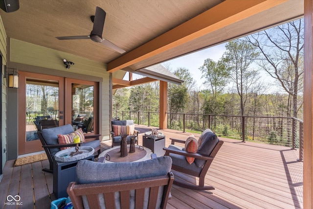 wooden deck with french doors, an outdoor hangout area, a ceiling fan, and a wooded view