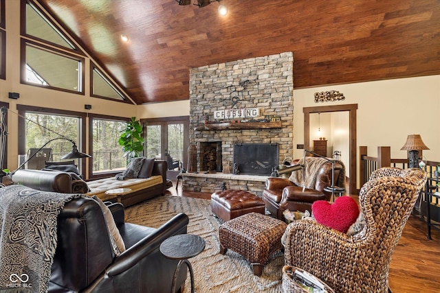 living room featuring high vaulted ceiling, wood finished floors, a stone fireplace, and wooden ceiling