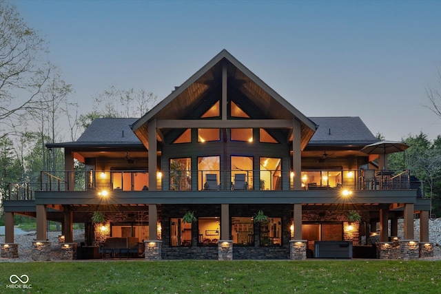 back of house featuring a balcony and a yard