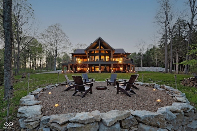 rear view of property with a fire pit, a lawn, and a deck